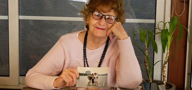 Flutura Xhabija, at 76, pictured with photo prints of her participation in Beijing in 1995. Photo: UN Women/Yllka Parllaku